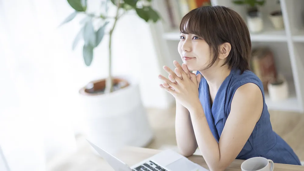 パソコンの前で笑顔で考える女性