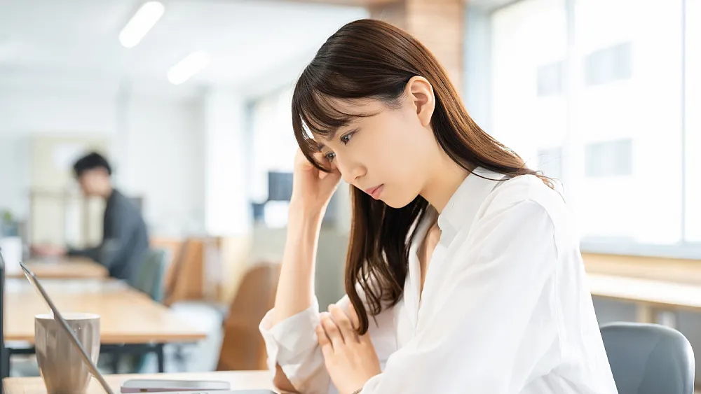 パソコンを使いながら考える女性