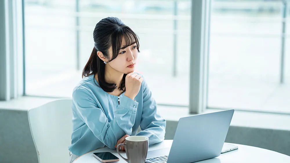 パソコンの前で悩む女性