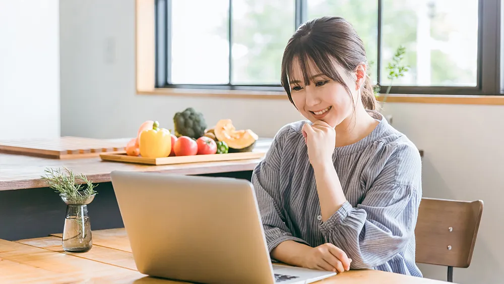 家でパソコンで仕事をす笑顔の女性